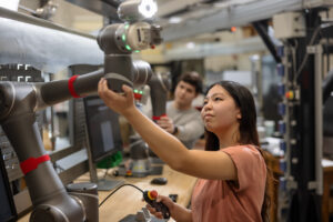 IMSE student interacting with a robot in anindustrial lab.