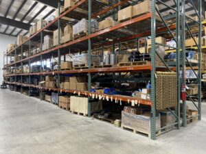 a well organized industrial warehouse with tall metal shelving units filled with various labeled boxes, crates, and containers